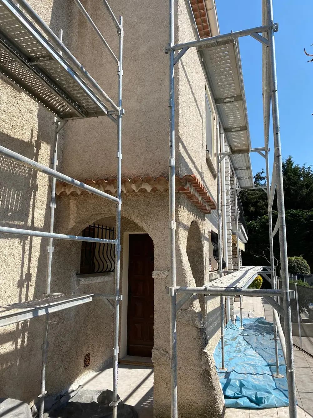 Entrée sous échafaudage, arc en plein cintre et porte bois protégés — Castagne Couverture