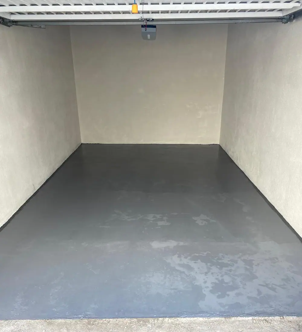 Le même garage après travaux, murs enduits et sol traité en résine — Castagne Couverture